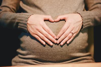 Femme enceinte qui fait un cœur avec ses mains.