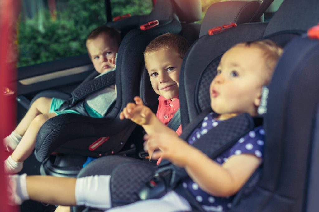 Les 3 enfants dans la voiture sont confortablement installés dans leur siège auto.