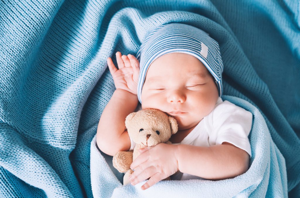 Ce bébé dort paisiblement avec son doudou.