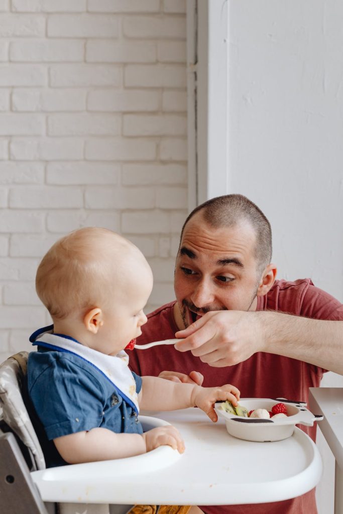 Ce bébé est en train de prendre son repas sur une chaise haute.