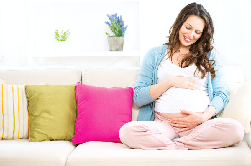 Cette future maman est assise sur un canapé.