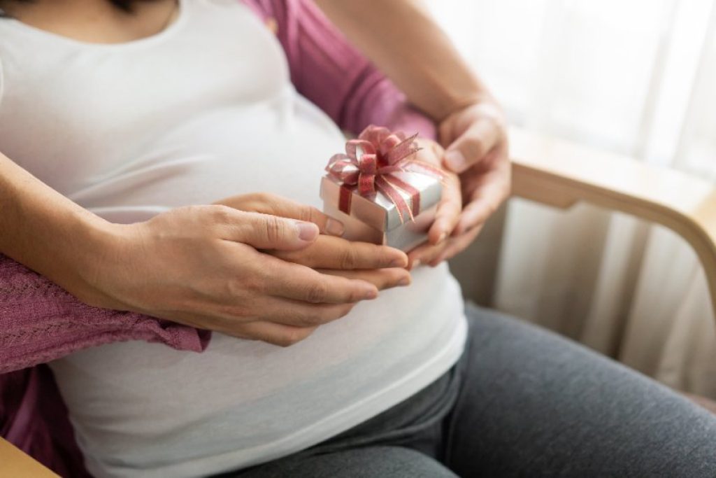 Cette femme enceinte a un cadeau entre ses mains.