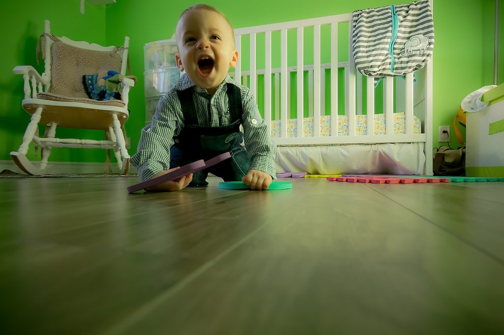 Cet enfant joue au sol dans sa chambre.