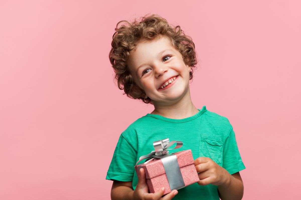 Ce jeune garçon tient un cadeau dans ses mains.