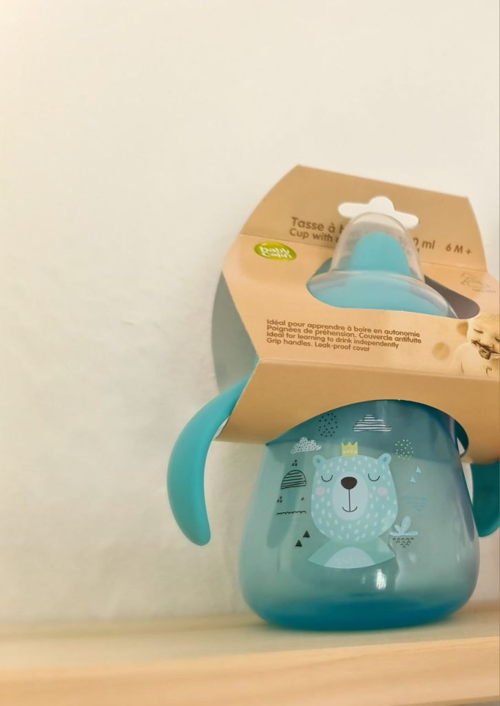 Cette tasse d'apprentissage pour bébé Babycalin est bleu avec un motif d'ours.